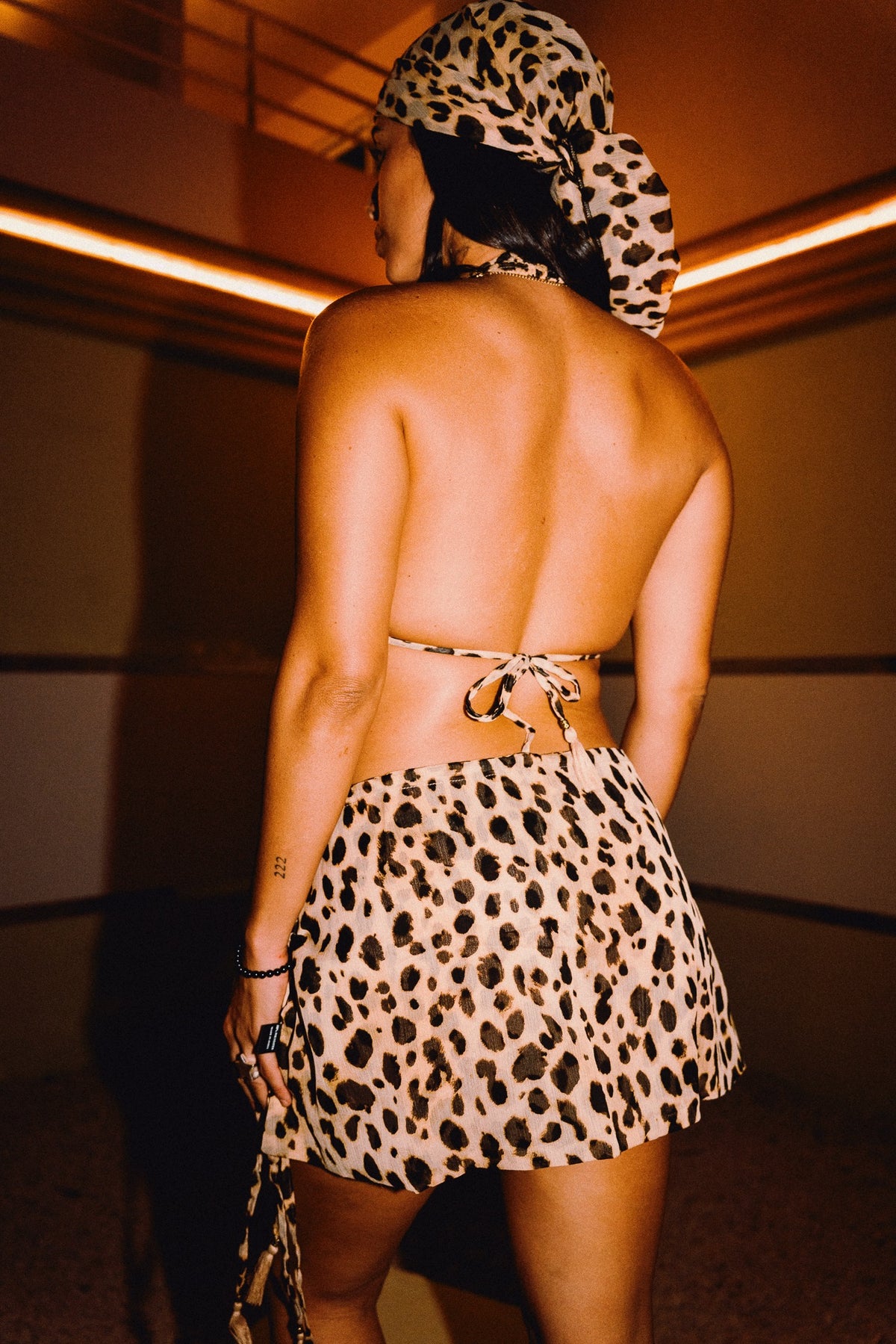 Back view of CHICHI cheetah print mini skirt with matching halter top and head scarf