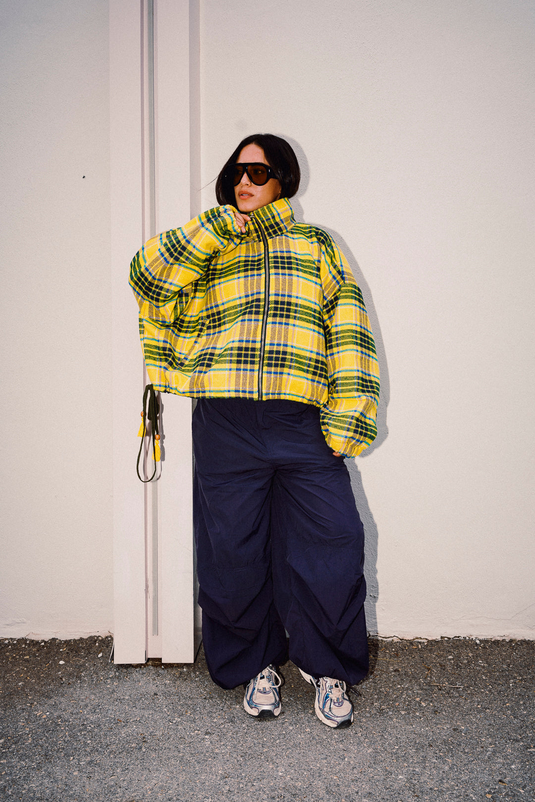 Woman wearing STOOP yellow checked fleece jacket with navy trousers