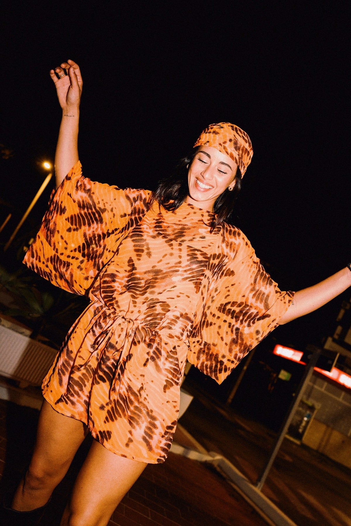 SOLARA orange tie-dye headscarf styled with matching mini dress – editorial photograph 00549